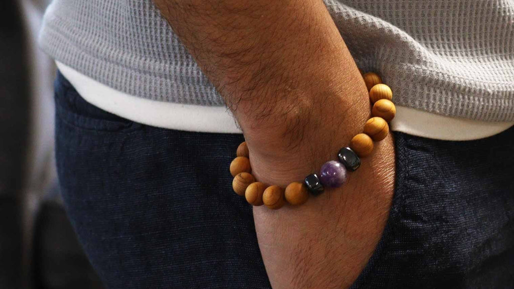 Person wearing a bracelet with beads, standing indoors.